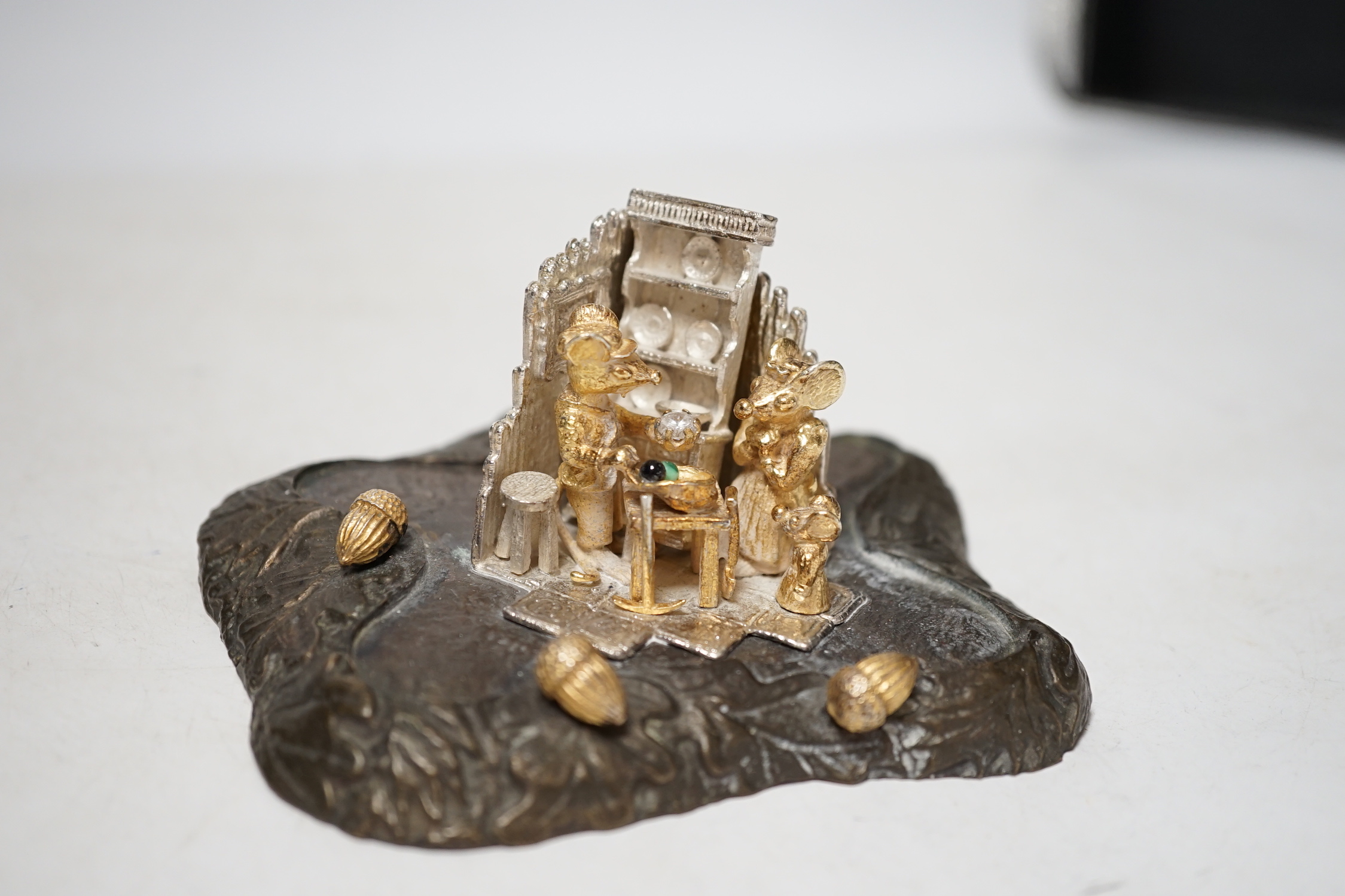 A limited edition Elizabeth II parcel gilt silver and base metal model by Christopher Nigel Lawrence, depicting pixies upon a tree stump, opening to reveal mice in kitchen scene, numbered 20/250, height 11.2cm.